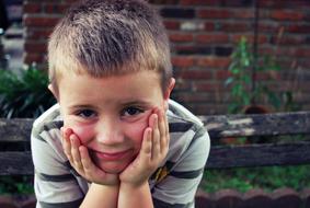 the boy pokes his hands on his cheeks
