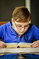 serious young boy reading book