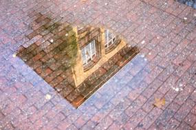 the corner of the building is reflected in a puddle