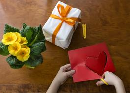 cut out of paper heart, yellow potted flower and a gift on the table