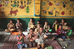 children sit on the floor in an asian school