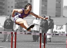 girl jumps over the Hurdles on a Track Race