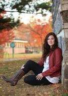 young girl sits on ground at autumn