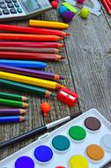 paints, pencils, sharpener and calculator on the table