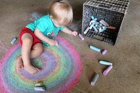 little boy draws with colorful crayons