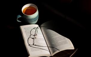 cup of tea and glasses on a book on the table