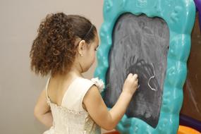 Child girl drawing with Chalk on Blackboard