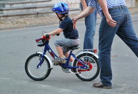man training Child Boy in blue helmet to ride bicycle