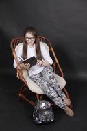 picture of sitting girl on a armchair with a book