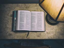photo of a table lamp and an open book on a vintage nightstand