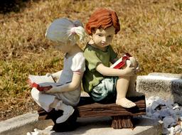 sculpture of a boy and a girl with books on a bench