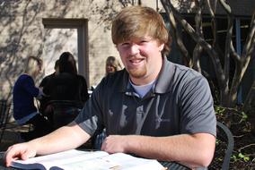 student is studying a textbook outdoors