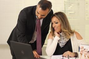 man and woman looking at the monitor screen in the office