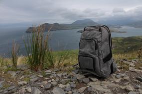 gray hiking backpack stands on the shore of a pond