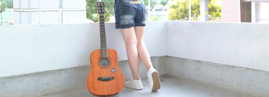 girl and acoustic Guitar stand at wall