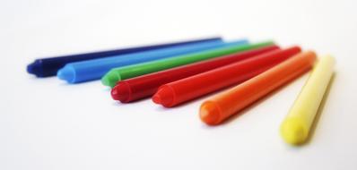school multi-colored wax crayons on white close-up on blurred background