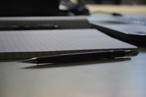 black automatic pencil and open notebook on the table