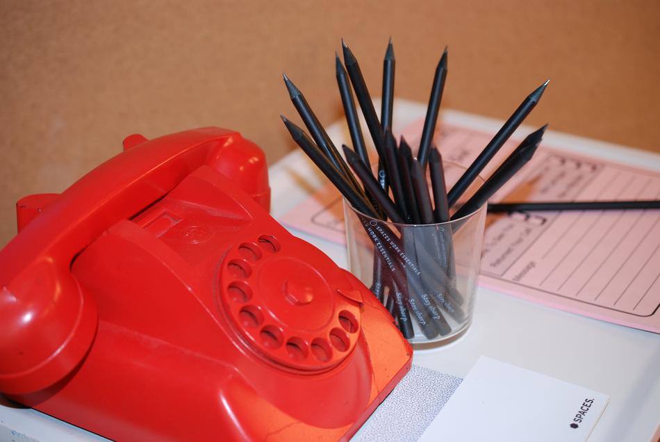 red phone near the glass with pencils on the table