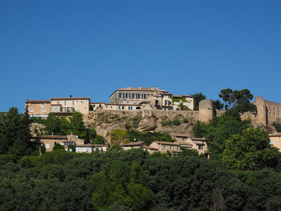 Beautiful landscape with the buildings of MÃ©nerbes, among the green plants, in France, under the blue sky