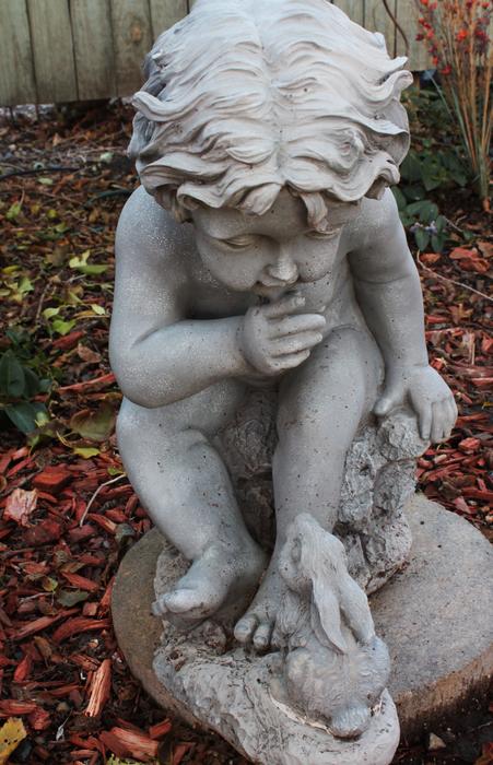 statue of a child in the autumn garden close up