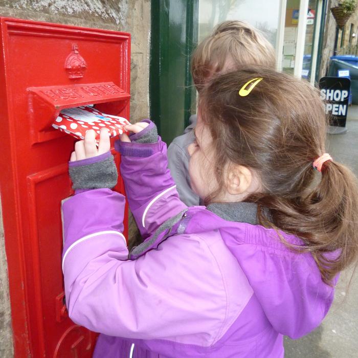 children with envelope near red mailbox