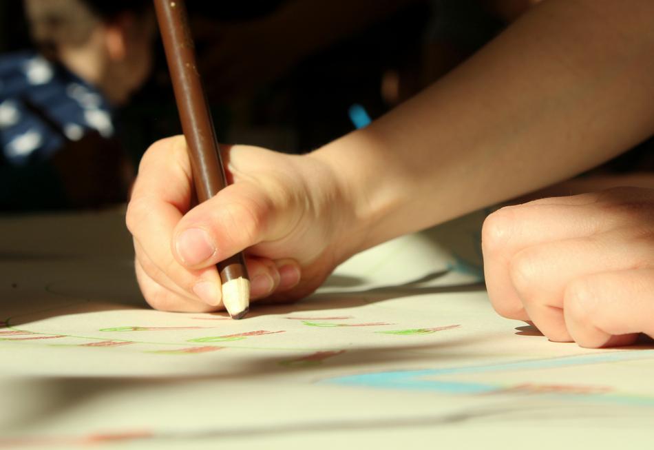 child draws with a brown pencil