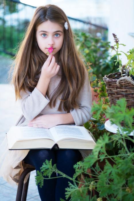 photo of a girl with a big book in the garden