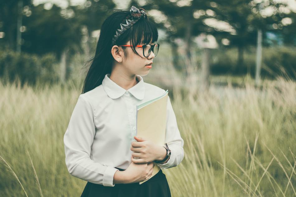 asian schoolgirl with books in the field
