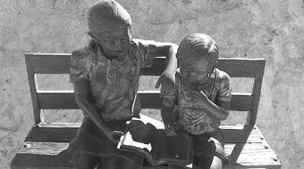 children with a book on the bench as a sculpture