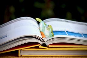 glasses and a pencil lie on an open book