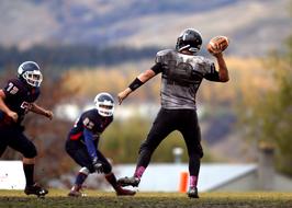 Players in equipment and uniform, playing American football, on the field, in Canada, on the competition