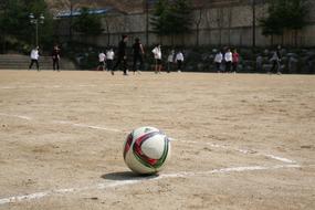 Players and colorful football, on the sand playground, with the white line, on the competition