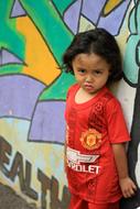 photo of a child on a background wall with graffiti