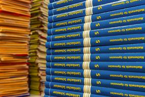 Blue and yellow math books in the stack, among the other books