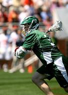 lacrosse player in green uniform attacking