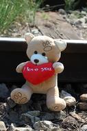 Teddy Bear with red heart in paws at rail