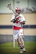 Lacrosse player, in the colorful equipment, on the green grass field
