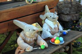 Cute and beautiful Easter bunny figures with colorful Easter eggs on the wooden bench