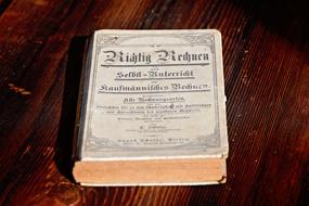 Beautiful, old antique book, on the brown wooden surface, in light