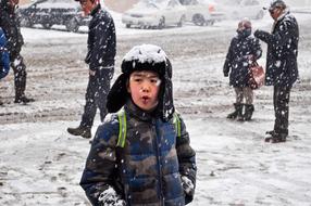 a schoolboy stands under a snowfall in Mongolia