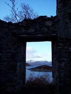 scenic coastline at dusk, view through doorway in aged stone wall, Scotland