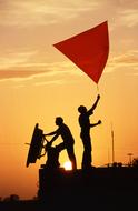 silhouettes of scientists with a radar dish at sunset