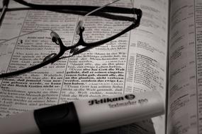glasses and marker on open book close up