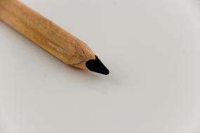 Close-up of the beautiful, black end of the wooden pencil, on the white surface