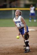 Smiling softball female pitcher with ball, on the sand