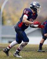 American football player in colorful uniform, on the green grass field, on the competition
