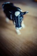 Close-up of the cute and beautiful, black and white cow figure on the wooden surface