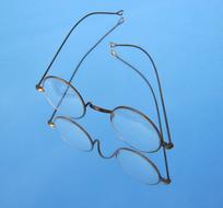 Close-up of the shiny reading glasses, on the blue surface, with the reflection