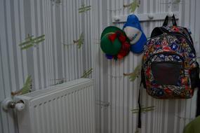 Colorful backpack, cap and hat, hanging in the room