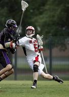 Lacrosse players, with the colorful equipment, on the green grass field, on the competition